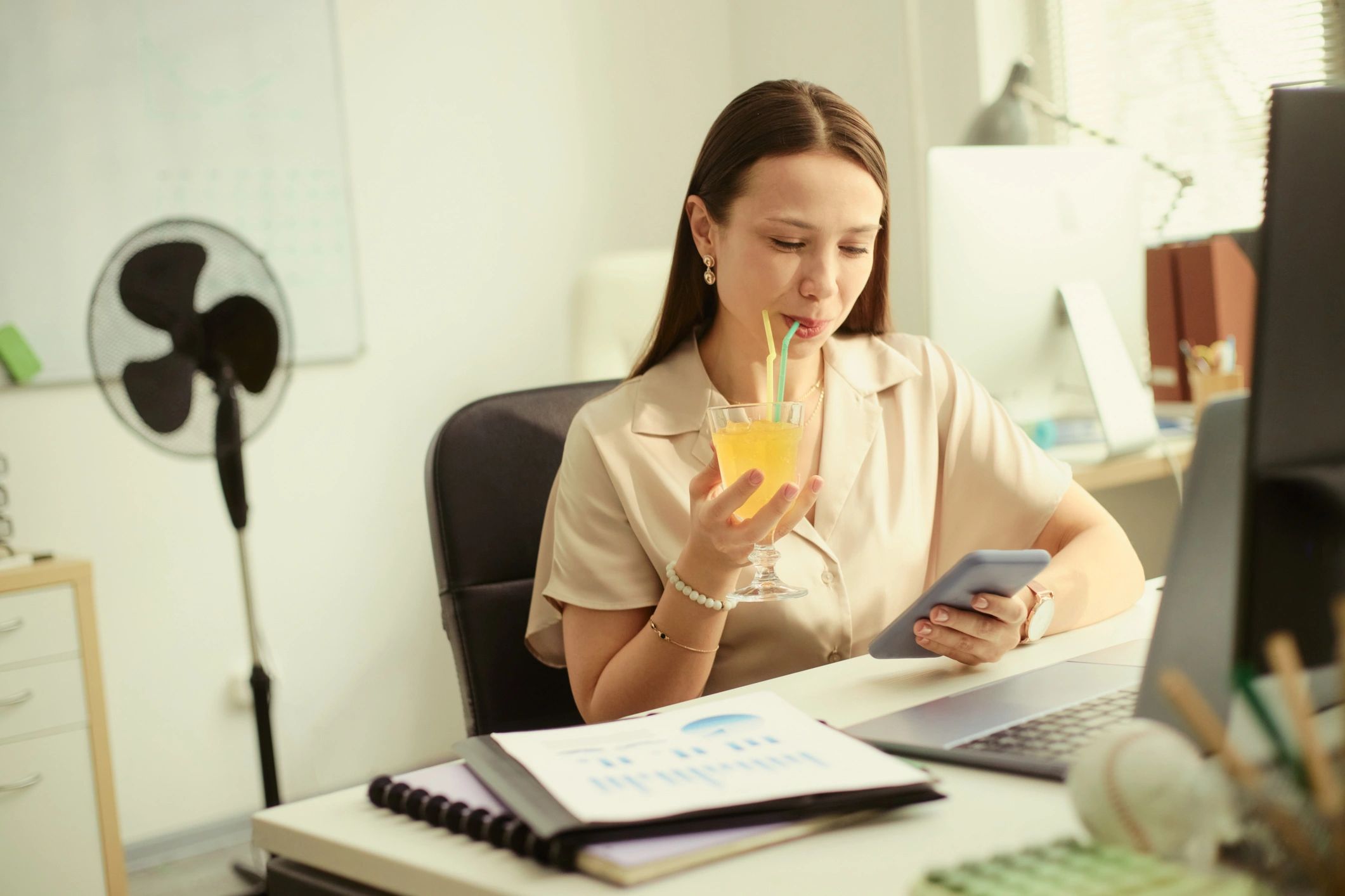 Professional woman checking smartphone at office desk